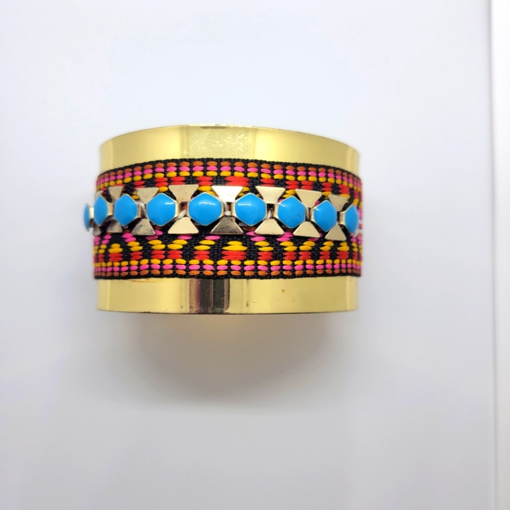 Gold tone cuff with embroidery and blue stone details.